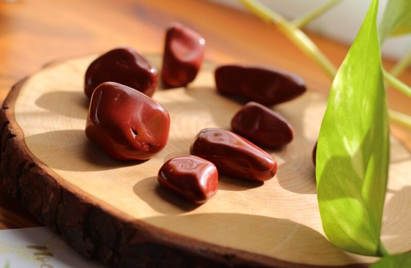 Conjunto de cantos rodados de jaspe rojo sobre rodaja de madera